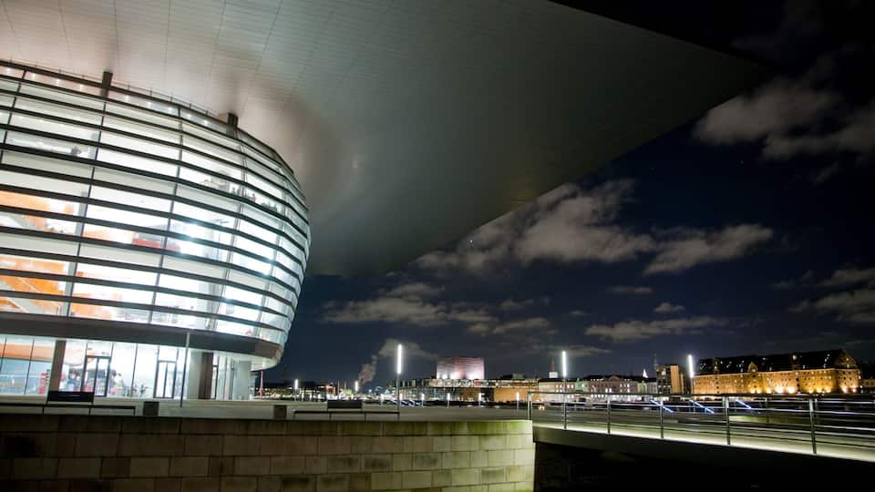 A modern building with a curved facade and a glass exterior, under a large overhang.