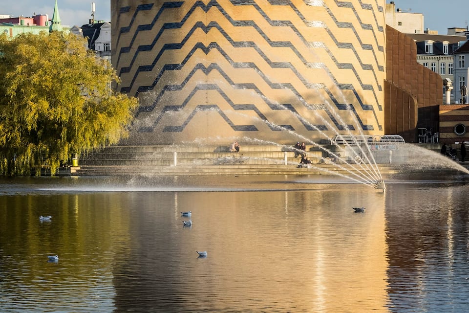 A modern building with a curved facade and a fountain in front.