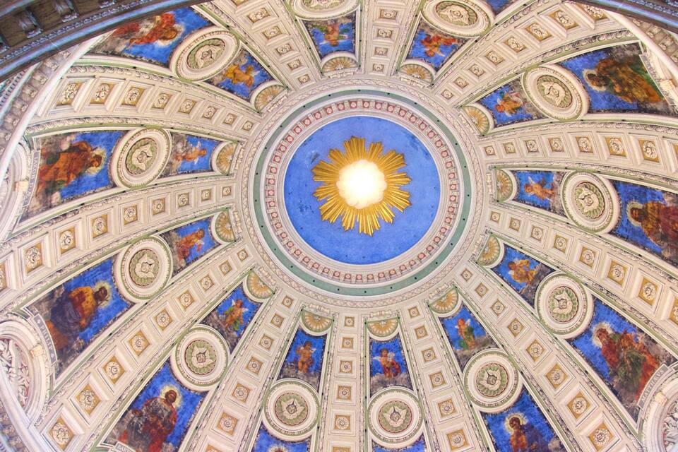 A detailed ceiling with a central sun-like design surrounded by intricate patterns and figures.