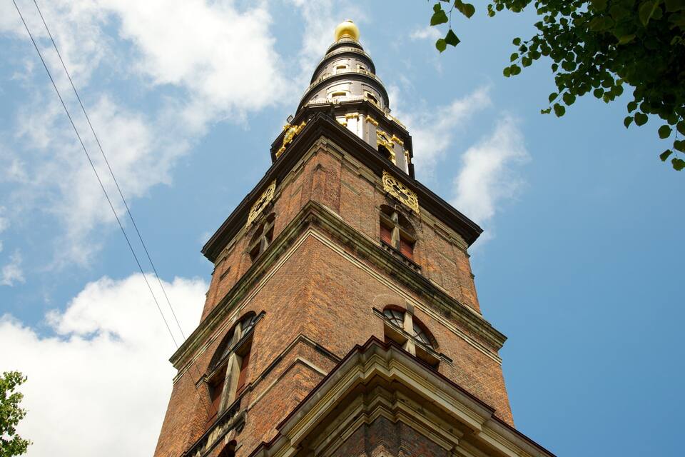 A tall brick tower with a golden dome and clock.