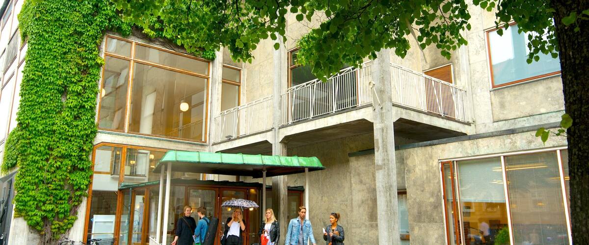 A building with a green awning, a bicycle, and a planter with flowers.