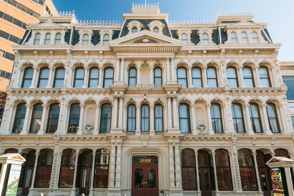 Um edifício histórico com arquitetura elaborada, grandes janelas e uma entrada imponente.