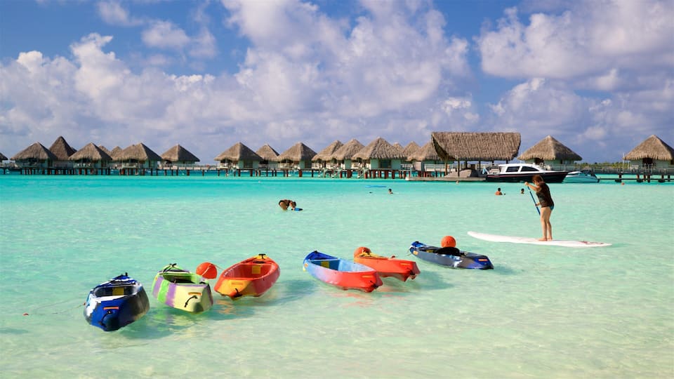 A turquoise beach with overwater bungalows and colorful kayaks.