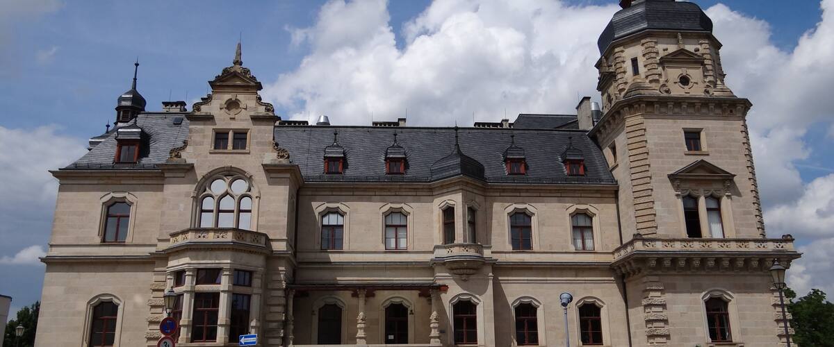 Um edifício grande e histórico com uma torre imponente e janelas em arco.