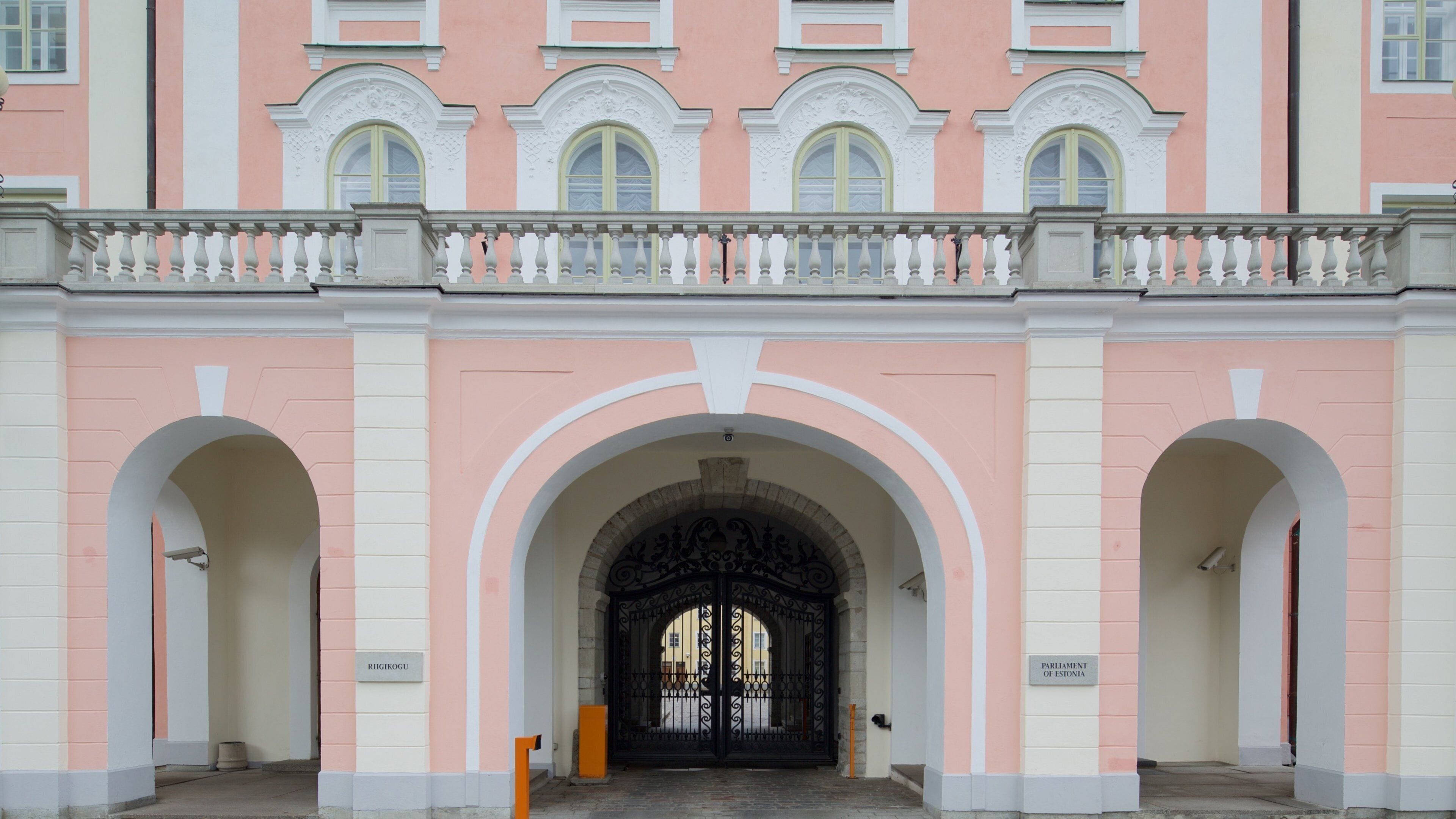 A building with pink and white walls, arched doorways, and a balcony with balustrades.
