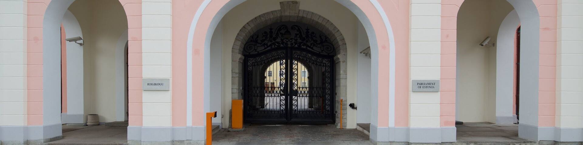 A building with pink and white walls, arched doorways, and a balcony with balustrades.