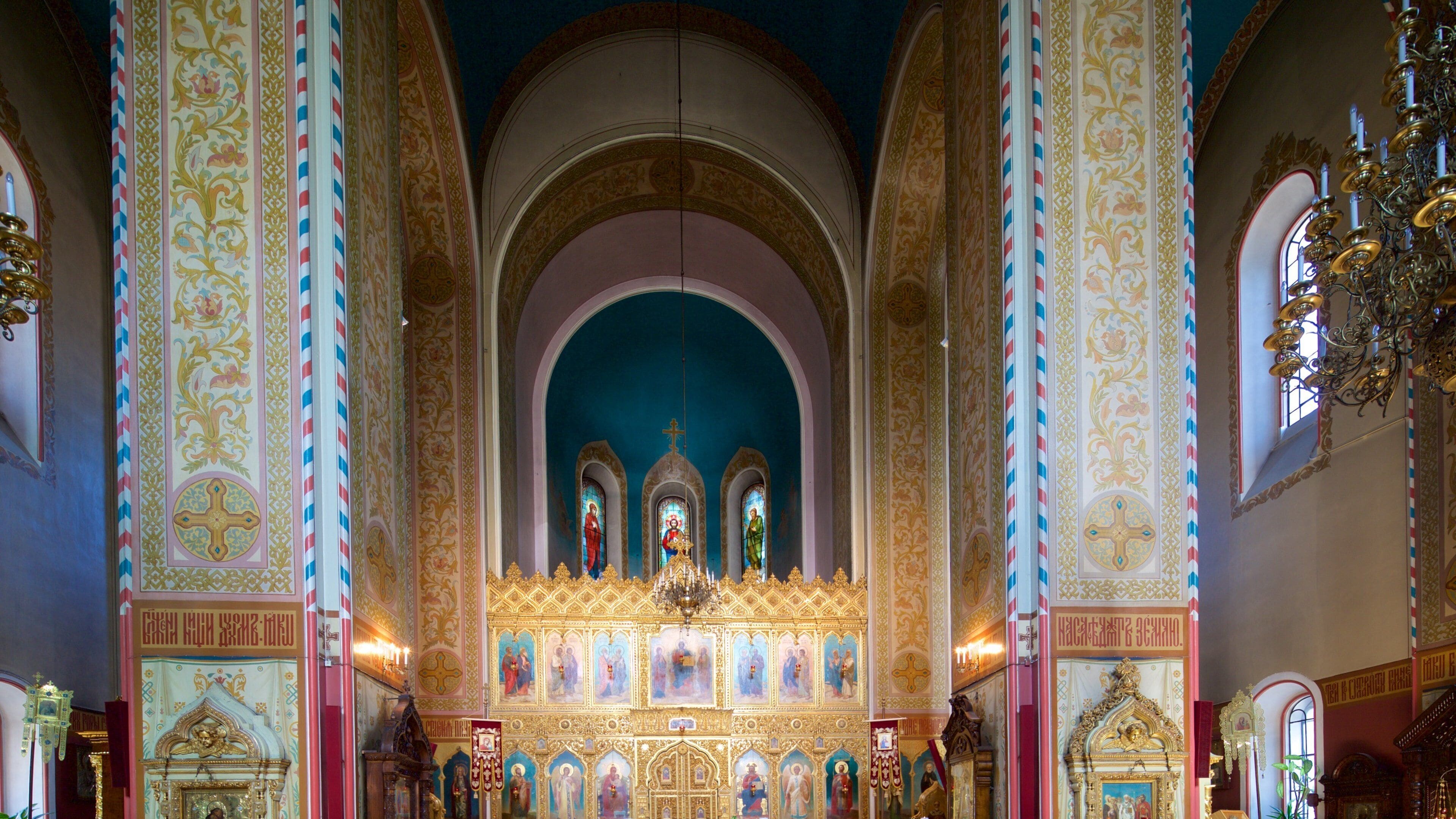 An ornate church interior with golden decorations, a central altar, and a blue ceiling.