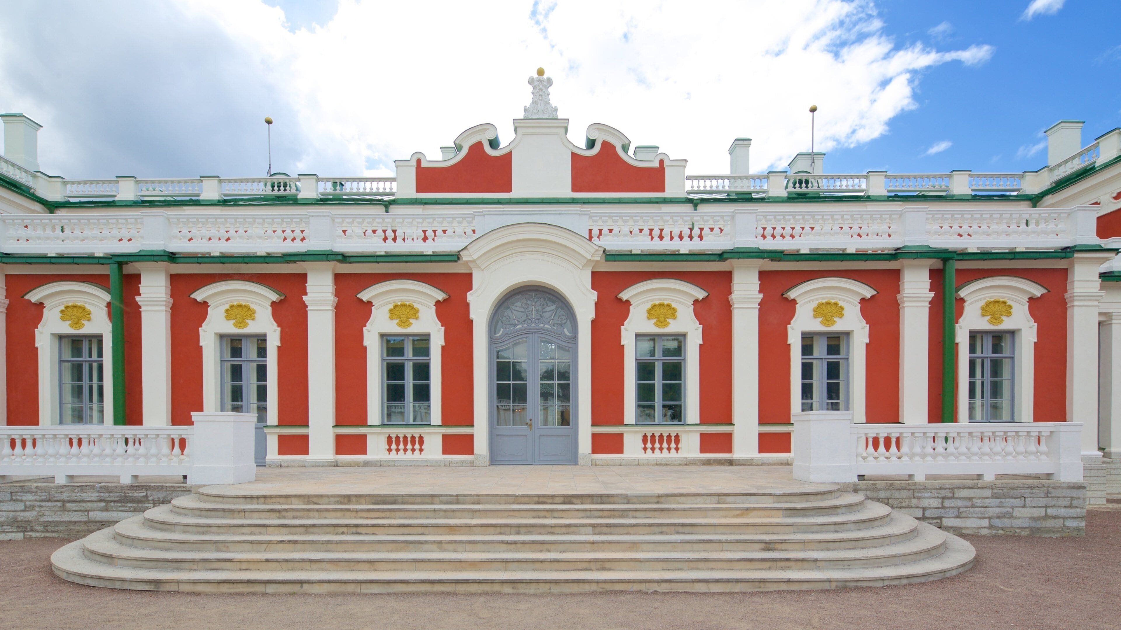 A red and white building with a central entrance, flanked by columns and decorative elements.