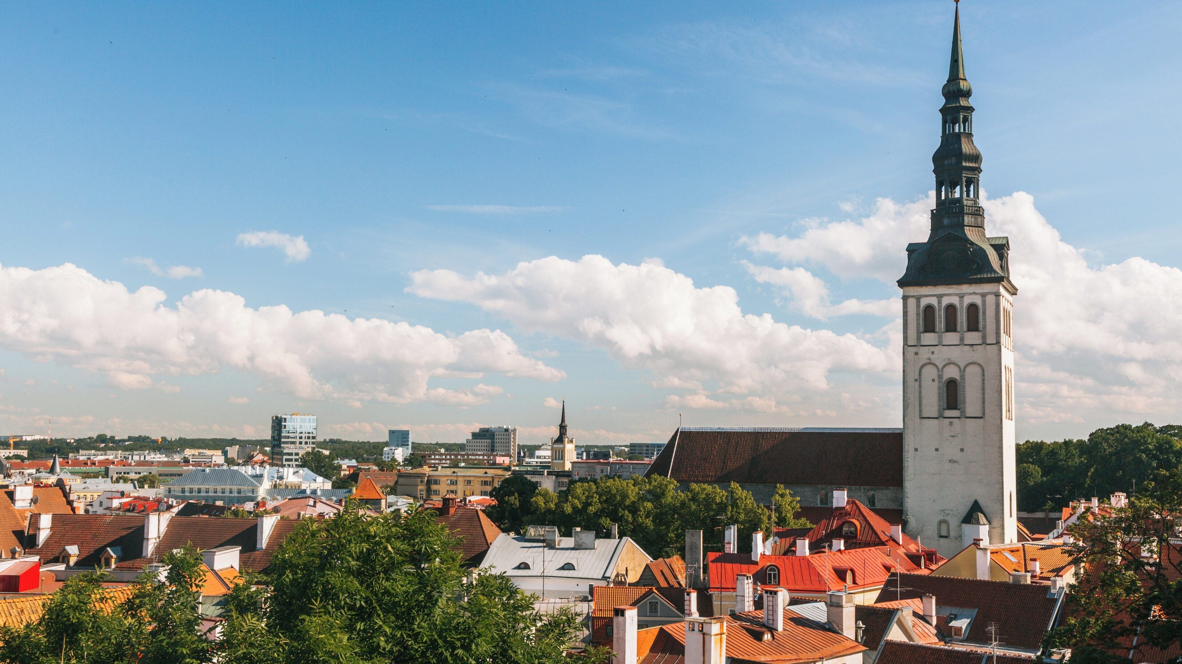St. Nicholas' Church towers above the beautiful rooftops of Old Town Tallinn in Harju County, Estonia, showcasing the historic architecture and vibrant city life
