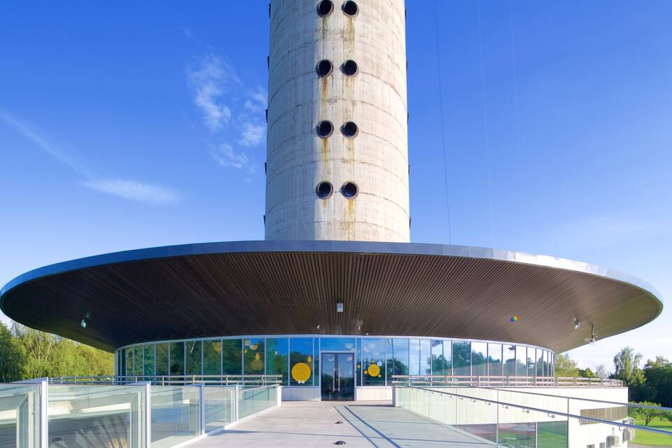 A modern tower with a circular observation deck and a glass entrance.