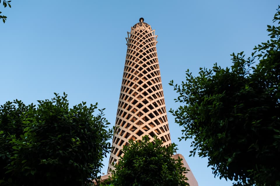 Un edificio alto con fachada enrejada, rodeado de árboles.