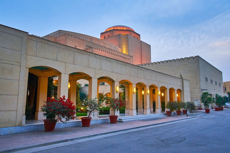 A building with a dome and arched windows, surrounded by potted plants.