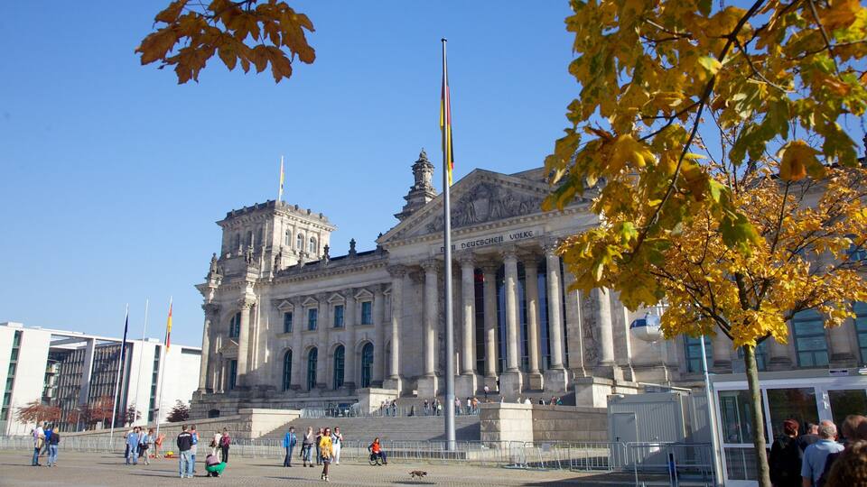 A historic building with classical architecture, a flagpole, and autumn leaves.