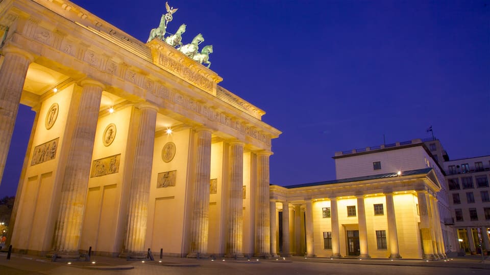 The Brandenburg Gate at night with illuminated columns and statues.