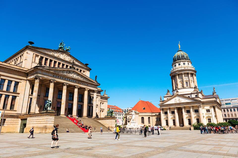 A large open plaza with historic buildings, including a prominent domed structure and a classical building with columns.