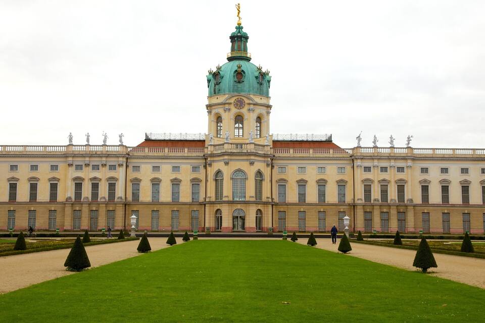 Un edificio histórico grande con una torre destacada y estatuas en el techo.