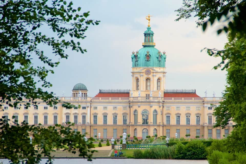 A large historic building with a prominent green dome and golden statues.