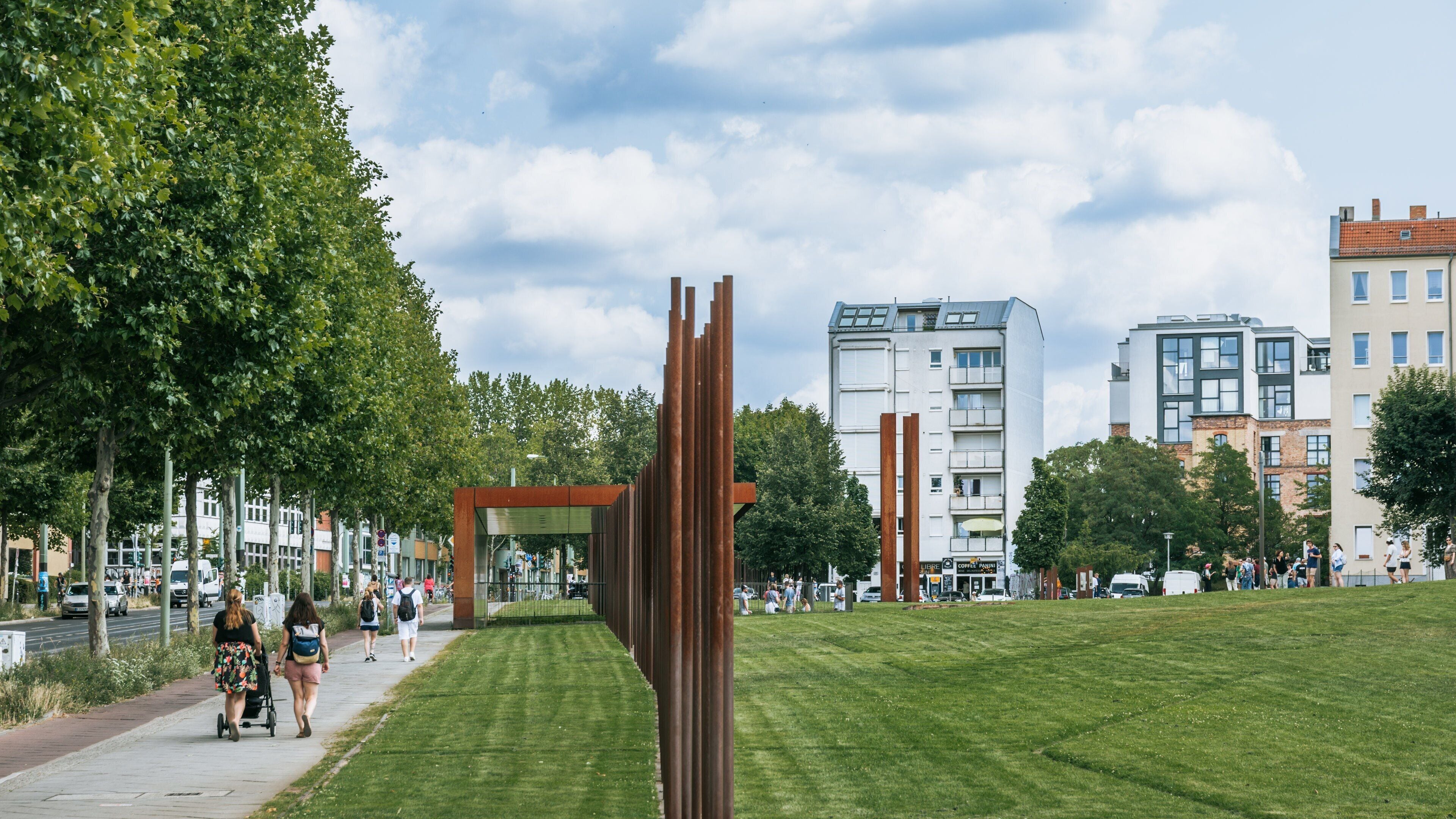 Un parc amb una escultura moderna, un camí i edificis urbans al fons.