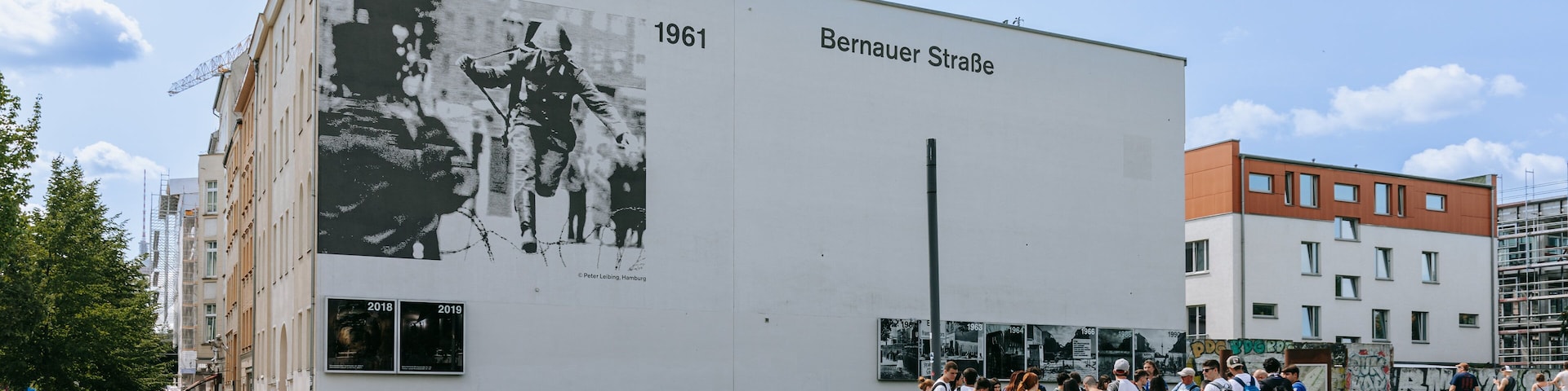 Um edifício com um grande mural em preto e branco e os dizeres "1961" e "Bernauer Straße".
