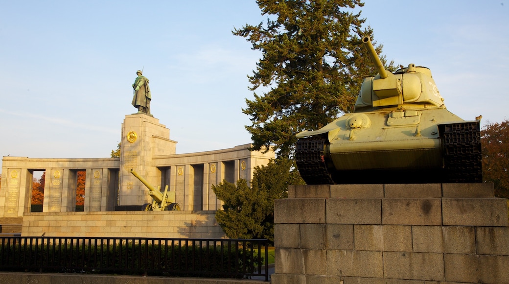 Tiergarten Soviet War Memorial showing military items, a statue or sculpture and a sunset