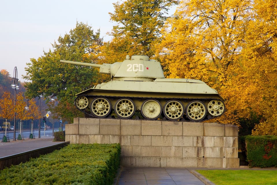 Un monument représentant un char d’assaut, portant le numéro 200, entouré d’arbres aux couleurs automnales et bordé d’une allée pavée.