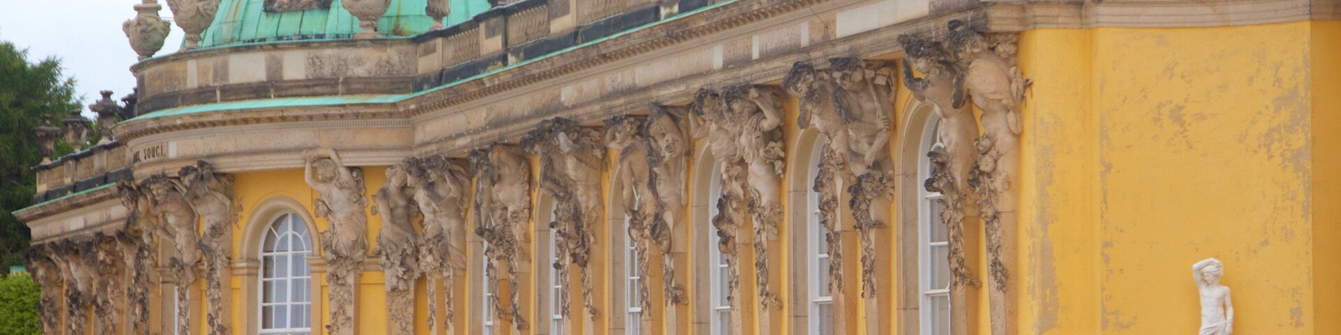 Un edificio imponente con esculturas ornamentales y una cúpula verde.