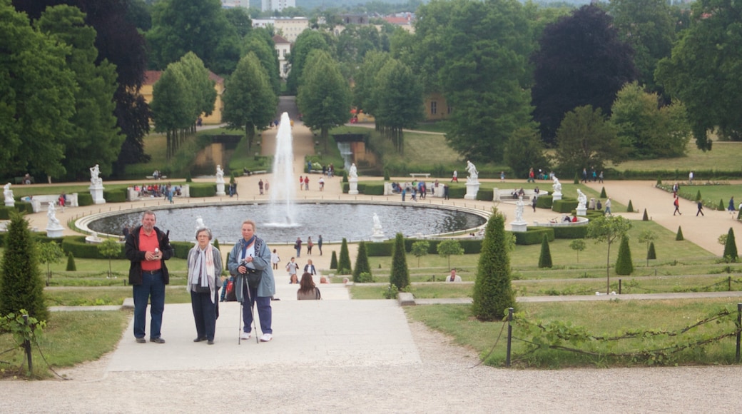 Palácio Sanssouci caracterizando uma fonte e um castelo assim como um pequeno grupo de pessoas