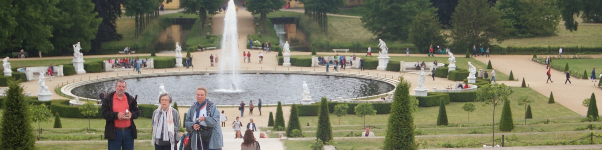 Sanssouci Palace featuring a fountain and a castle as well as a small group of people