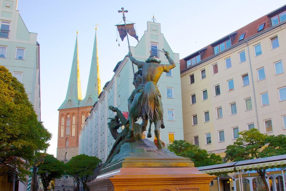A statue of a warrior on horseback in a city square, with historic buildings and spires in the background.