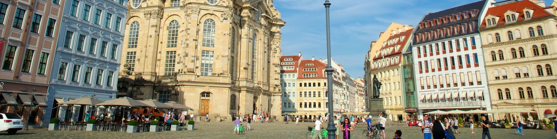 A historic building with a large dome and clock tower, surrounded by colorful European architecture.