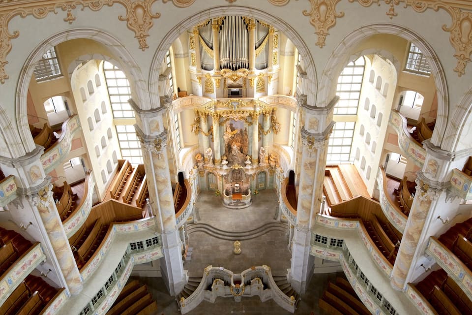 An ornate church interior with a central organ, arched ceilings, and intricate woodwork.
