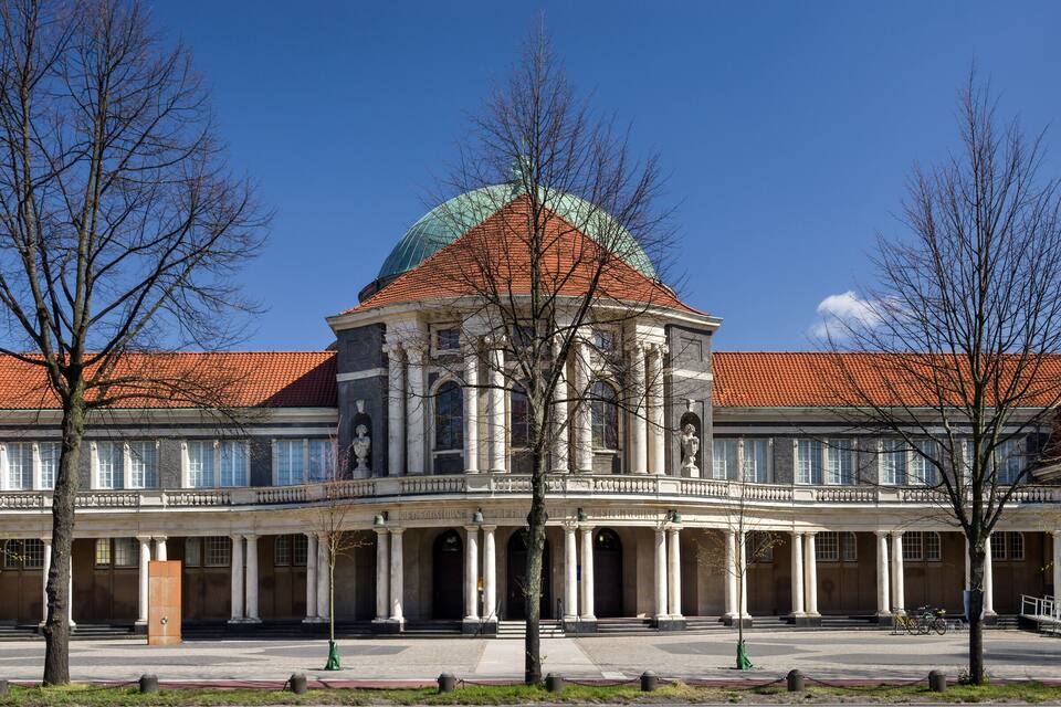 Ein historisches Gebäude mit rotem Ziegeldach, klassischen Säulen und einer zentralen Kuppel.