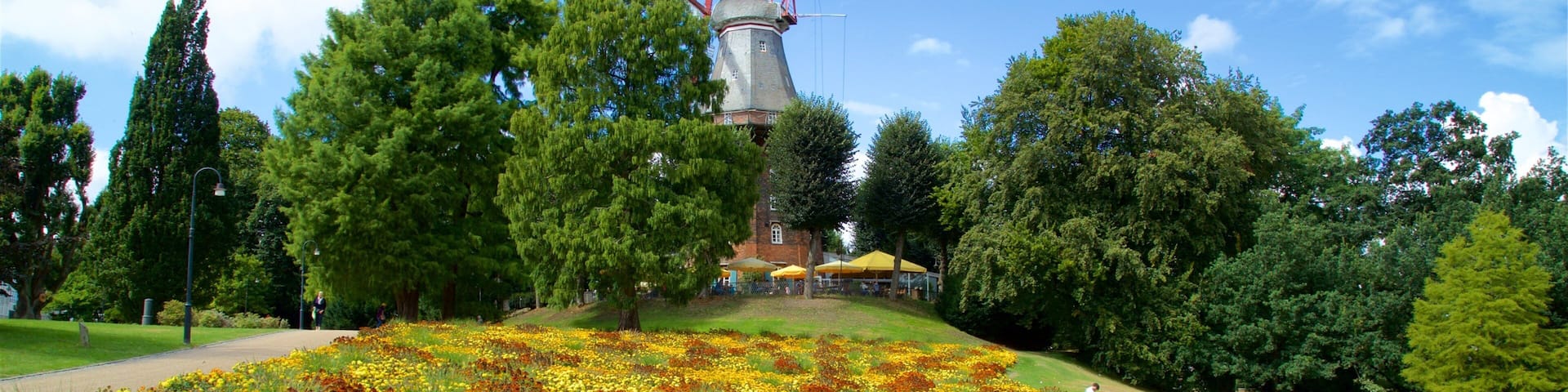 A windmill, a flower garden, and a pathway in a park.