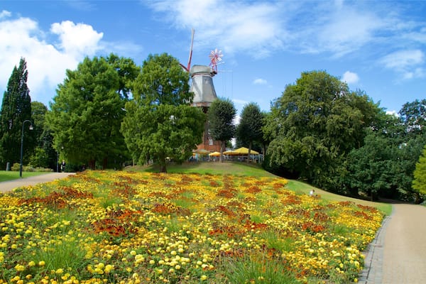 Eine Windmühle, ein Blumenbeet und ein Weg in einem Park.