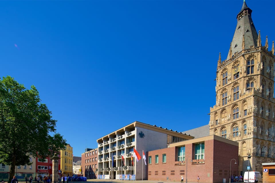 A historic tower with intricate architecture, a modern building with multiple floors, and a clear blue sky.