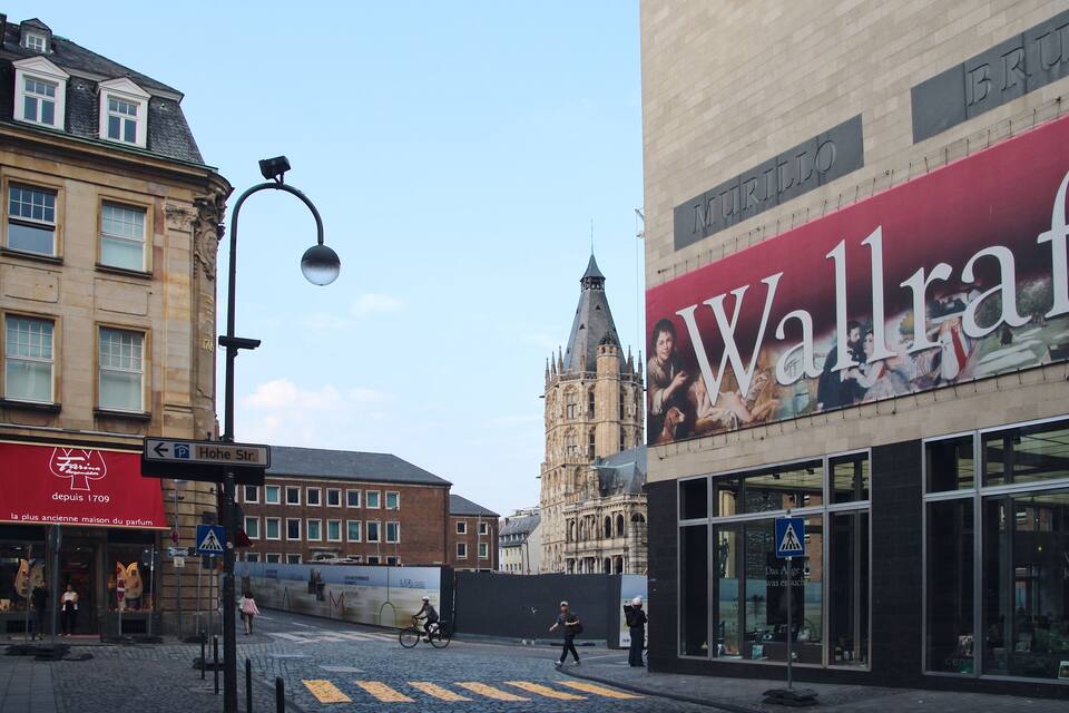 Calle con un gran mural, edificios históricos y una señal de tráfico que indica Hohes Str.