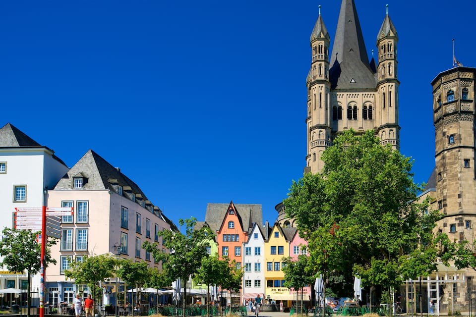 A historic church with twin spires, colorful buildings, and a clear blue sky.