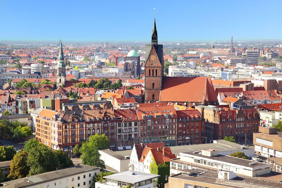 A cityscape with historic buildings, a prominent church tower, and a green dome.