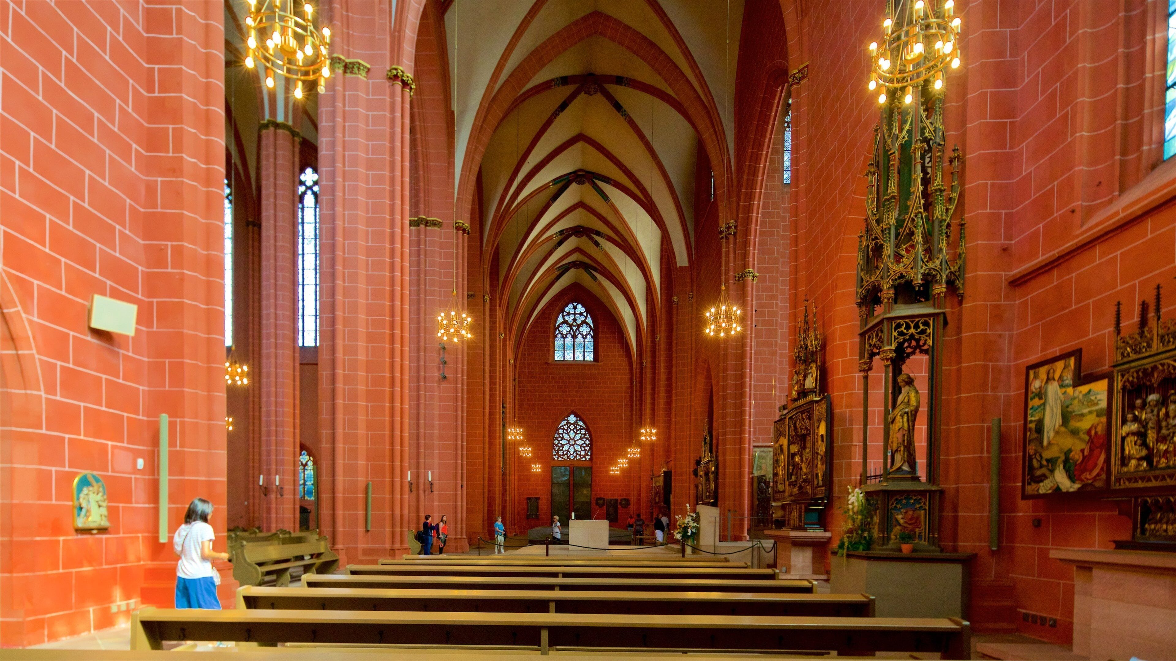 Een kerkinterieur met rode bakstenen muren, gewelfde plafonds en glas-in-loodramen.