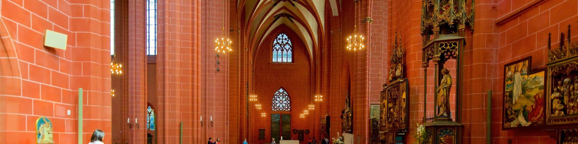 A church interior with red brick walls, arched ceilings, and stained glass windows.