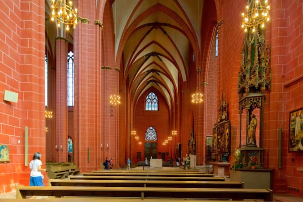 A church interior with red brick walls, arched ceilings, and stained glass windows.