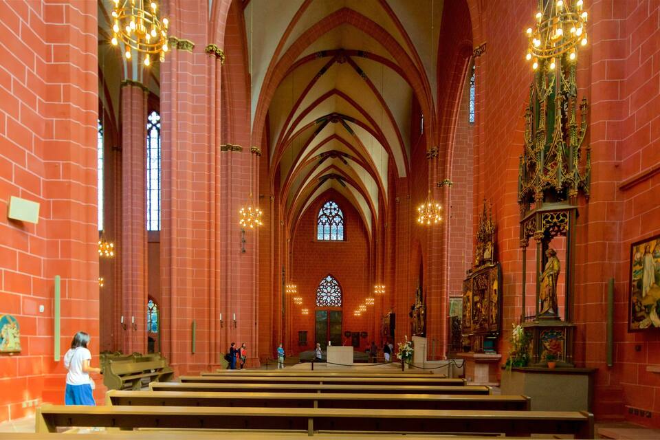 A church interior with red brick walls, arched ceilings, and stained glass windows.