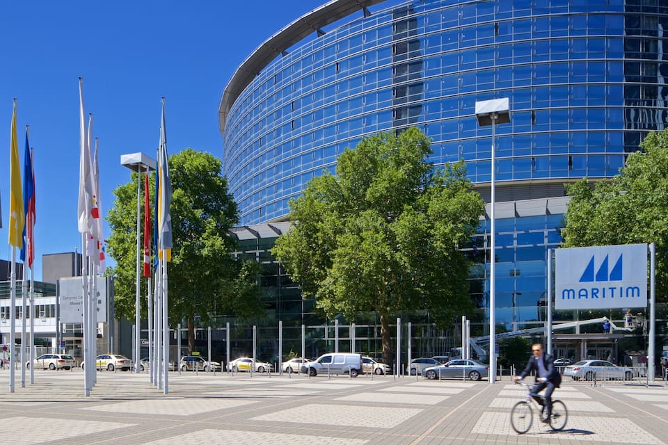 A modern building with a curved glass facade, flags, and a sign for 'MARITIM'.