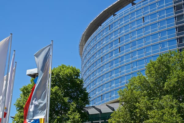 Ein modernes Gebäude mit einer geschwungenen Fassade und mehreren Flaggen davor.