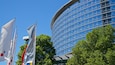 Ein modernes Gebäude mit einer geschwungenen Fassade und mehreren Flaggen davor.