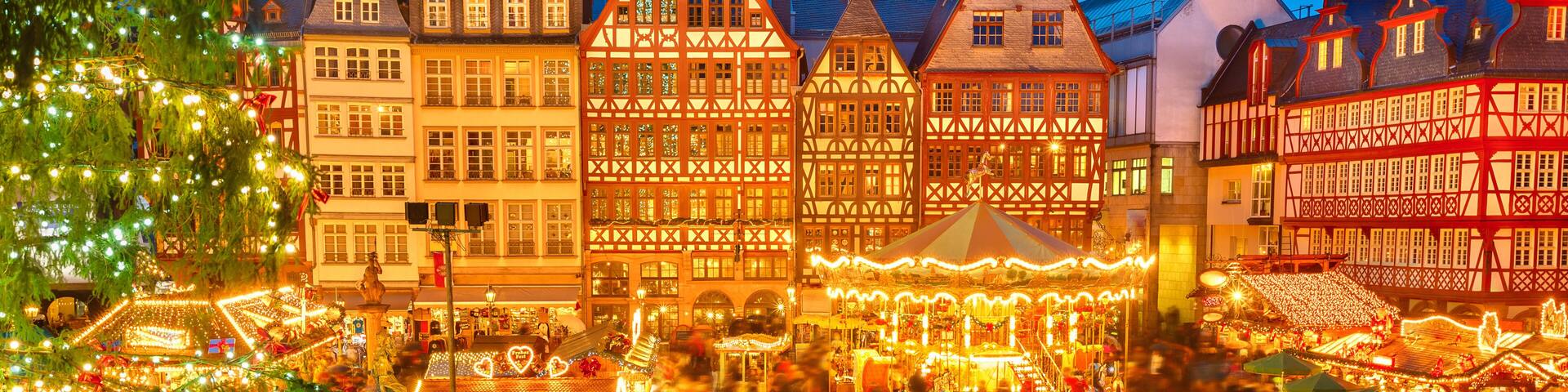 A Christmas market with traditional half-timbered buildings and a prominent church tower.