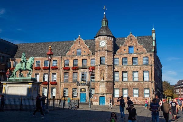 Un bâtiment historique doté d’une tour horlogée, d’une façade en briques rouges et d’une statue représentant un cavalier et son cheval.