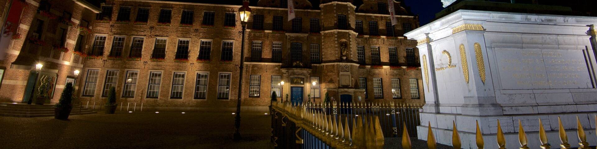 A historic building with a statue of a horse and rider, a clock tower, and a well-lit entrance.