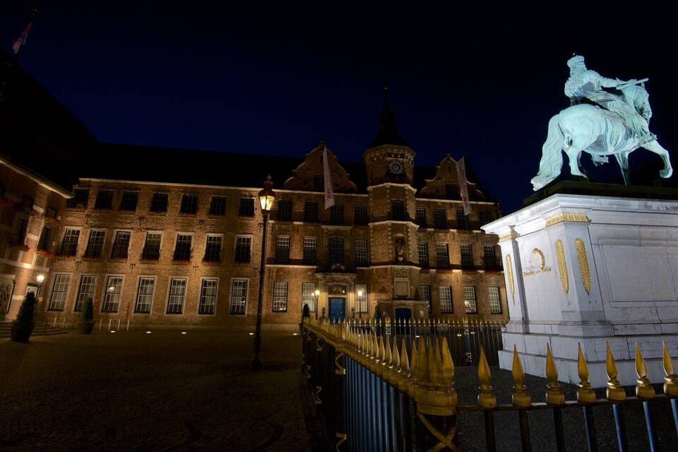 A historic building with a statue of a horse and rider, a clock tower, and a well-lit entrance.