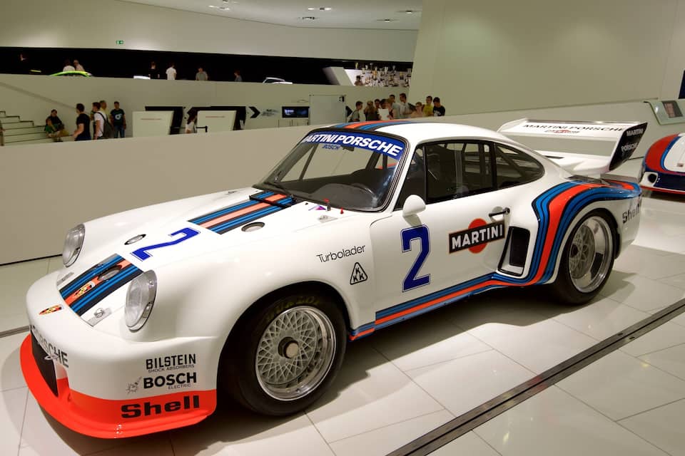 Een witte raceauto met blauwe en rode strepen, waarop nummer 2 en het woord "Turbolader" staan.